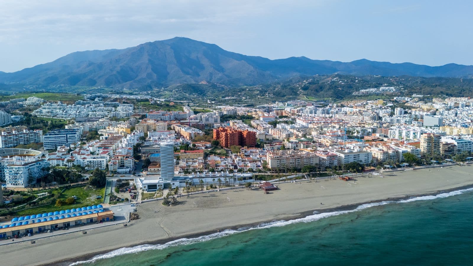 Luchtfoto van een Spaanse kustplaats aan de Costa del Sol met strand, witte bebouwing en bergen