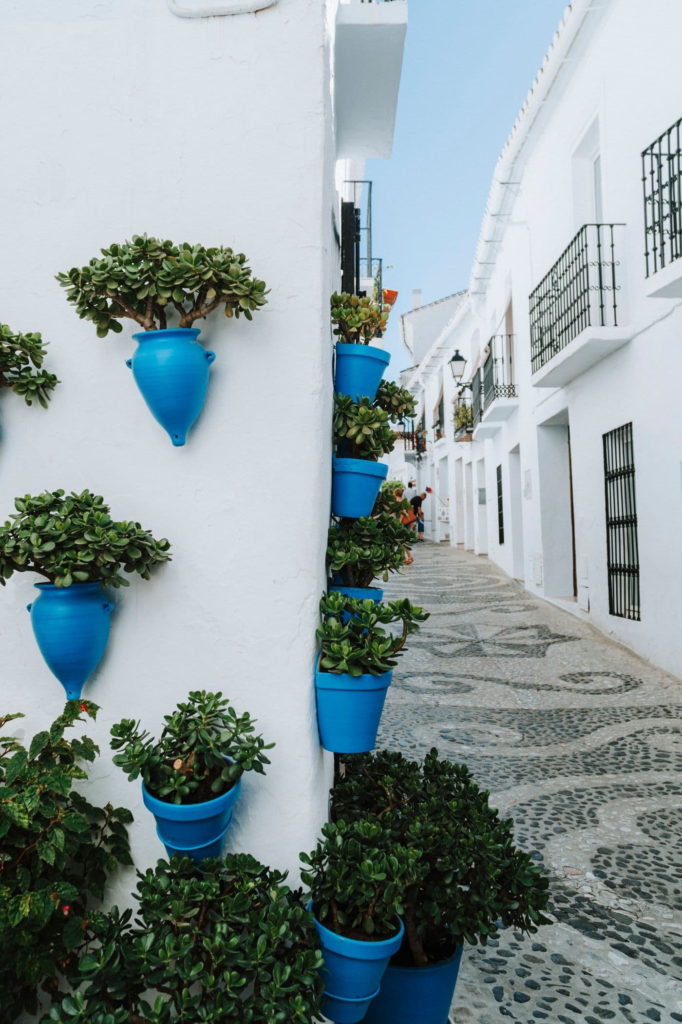 Wit straatje met blauwe potten in Frigiliana